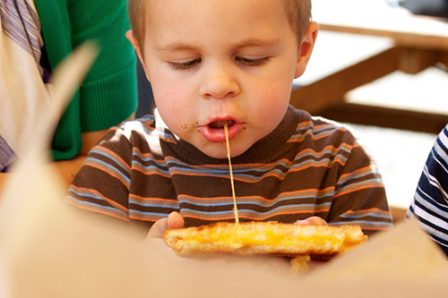 A young boy enjoys a grilled cheese sandwich.