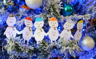 A depiction of a family with cut out paper people on a blue themed Christmas tree.