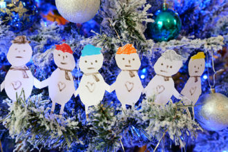 A depiction of a family with cut out paper people on a blue themed Christmas tree.