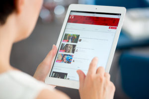 Kiev, Ukraine - May 21, 2014: Woman holding a brand new Apple iPad Air and looking on YouTube music playlist on a screen. YouTube is the world's most popular online video-sharing website that founded in February 14, 2005