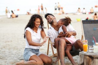 mother and father laughing on beach during summer vacation