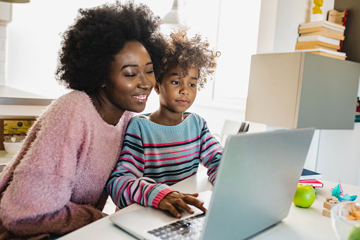 African American mother is teaching her daughter are using laptop at home together during back-to-school season