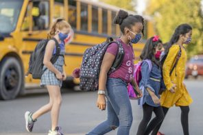 School Supplies for School from Office Depot. Students crossing the street wearing masks after getting off the school bus.