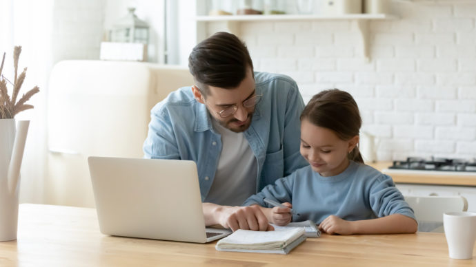 Dad working with daughter on laptop