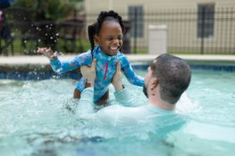 Girl swimming in pool with dad