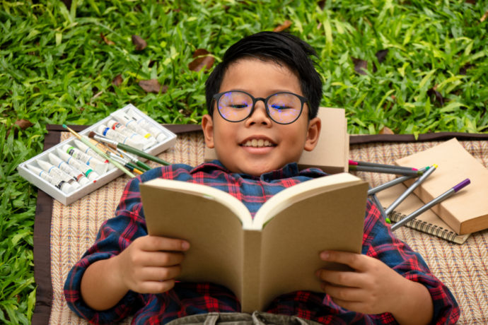 Child reading book outside