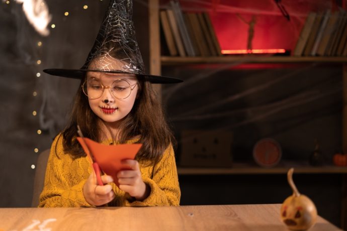 Child dresses as a witch doing a Halloween craft