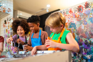 kids mixing paint and wearing art frocks