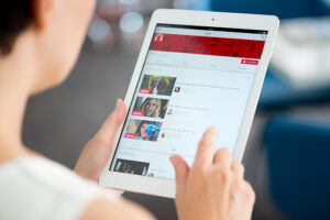Kiev, Ukraine - May 21, 2014: Woman holding a brand new Apple iPad Air and looking on YouTube music playlist on a screen. YouTube is the world's most popular online video-sharing website that founded in February 14, 2005