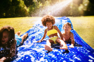 Afro girl and friends playing on a water slide